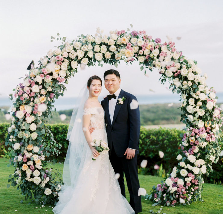couple portrait in front of the lush circular wedding arch of pastel florals