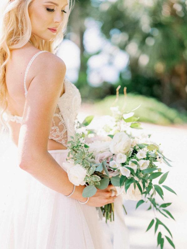 the bride looking down at her lush bridal bouquet