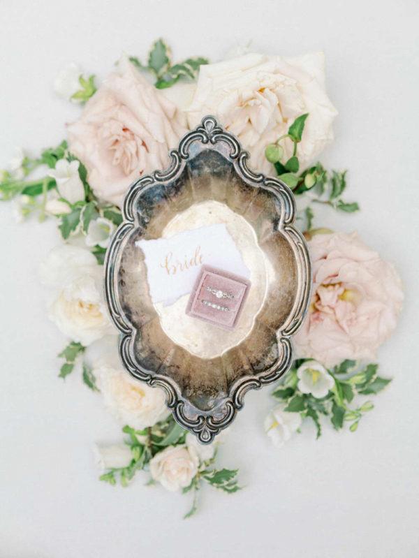 weddings rings in a pink box set on a silver platter surrounded by florals