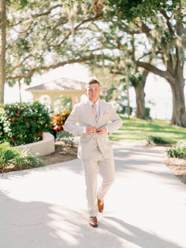 groom buttoning his suit jacket for his Florida wedding