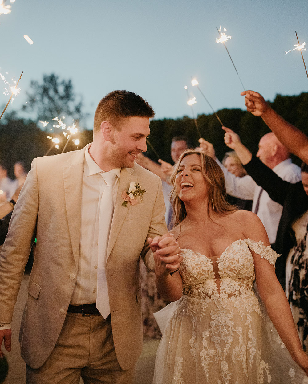 Sparkler sendoff with an off-the-shoulder wedding dress and tan groom suit