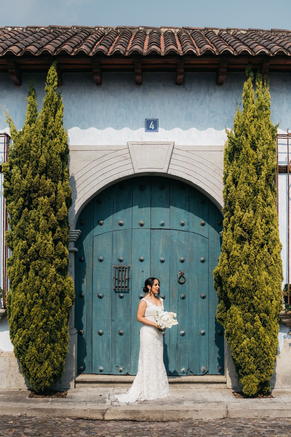 bridal portrait in front of large blue door with 2 large trees