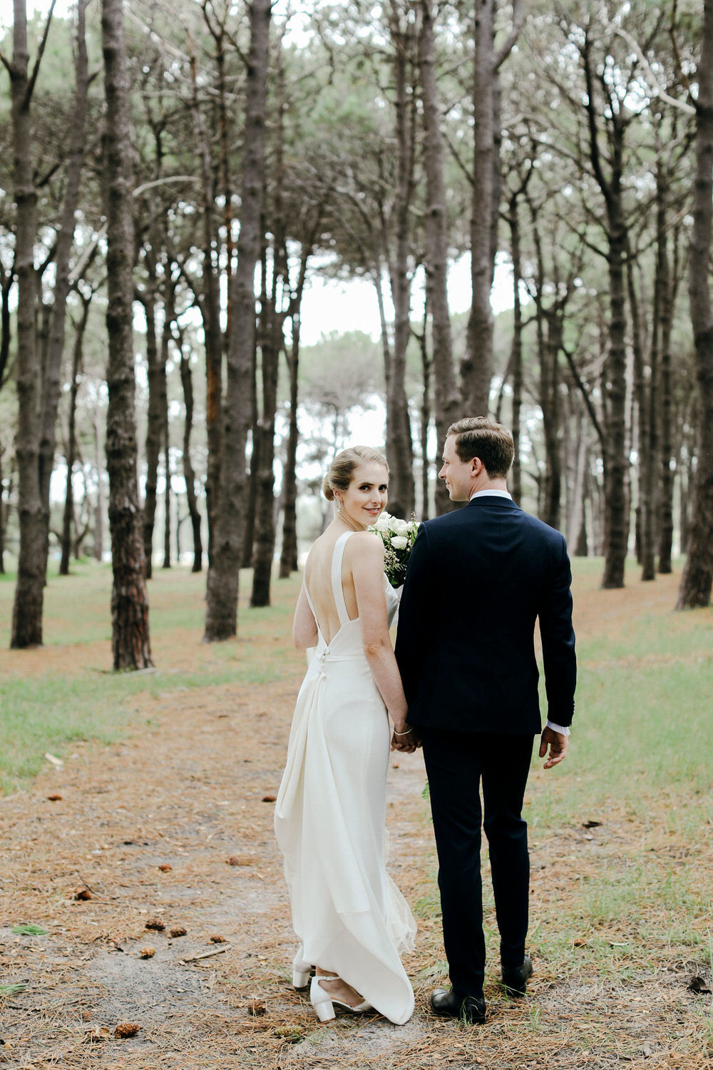 bride and groom walk together in the woods