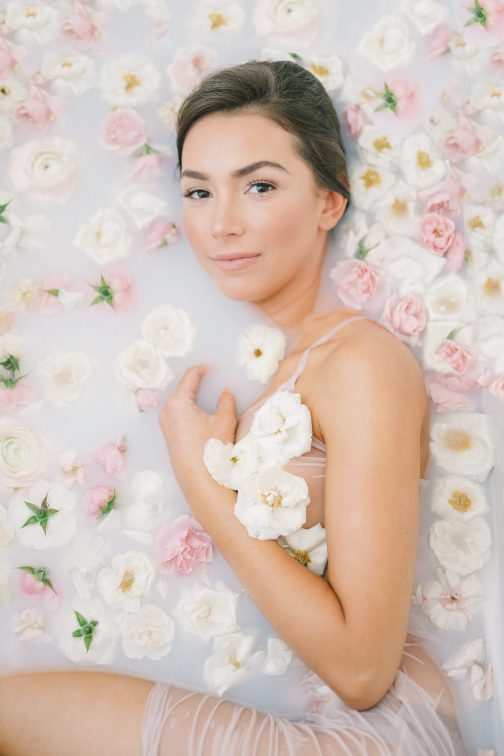 bride in a milk bath surrounded by pink and white flowers