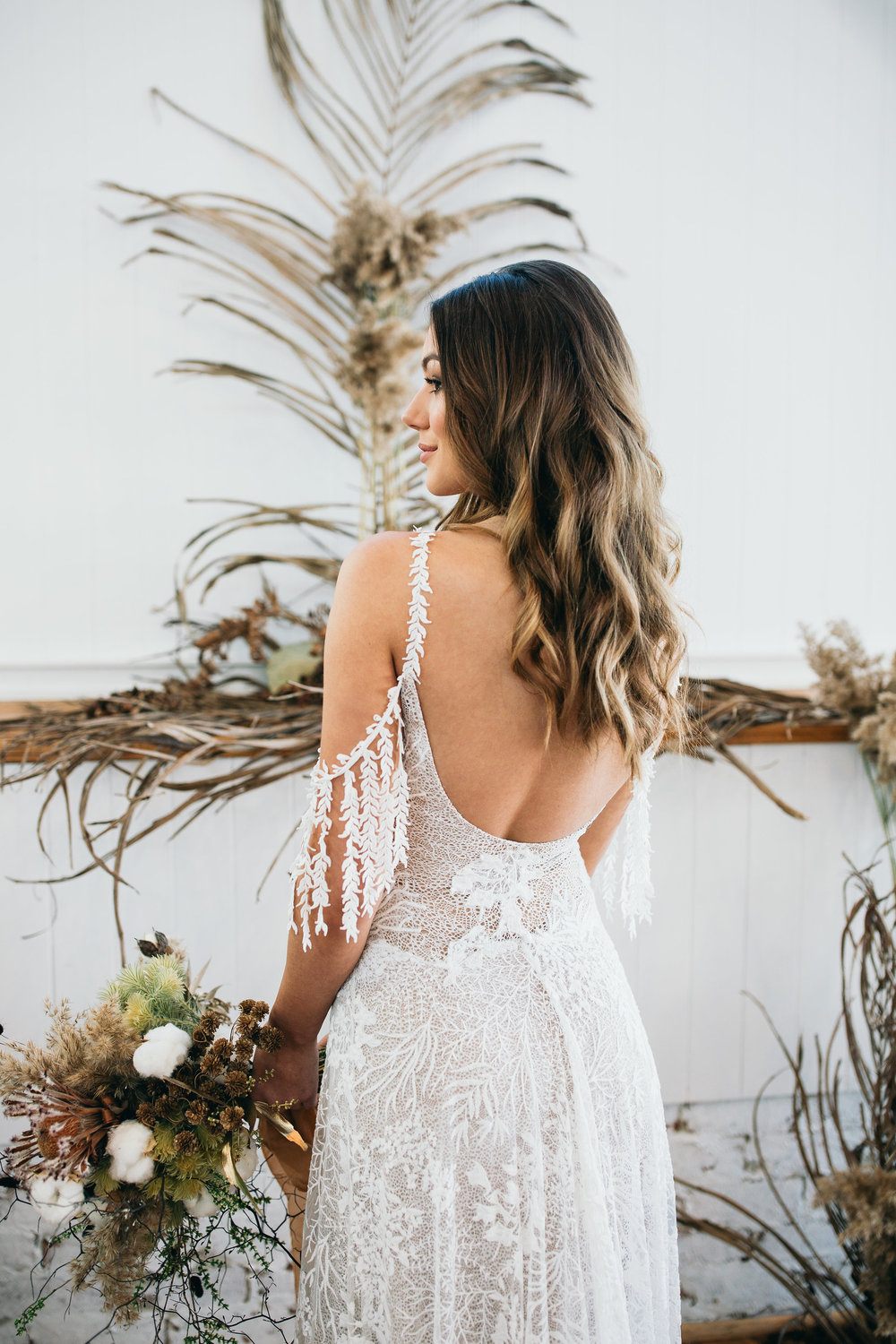 dried exotic foliage wedding backdrop with bride in boho wedding dress