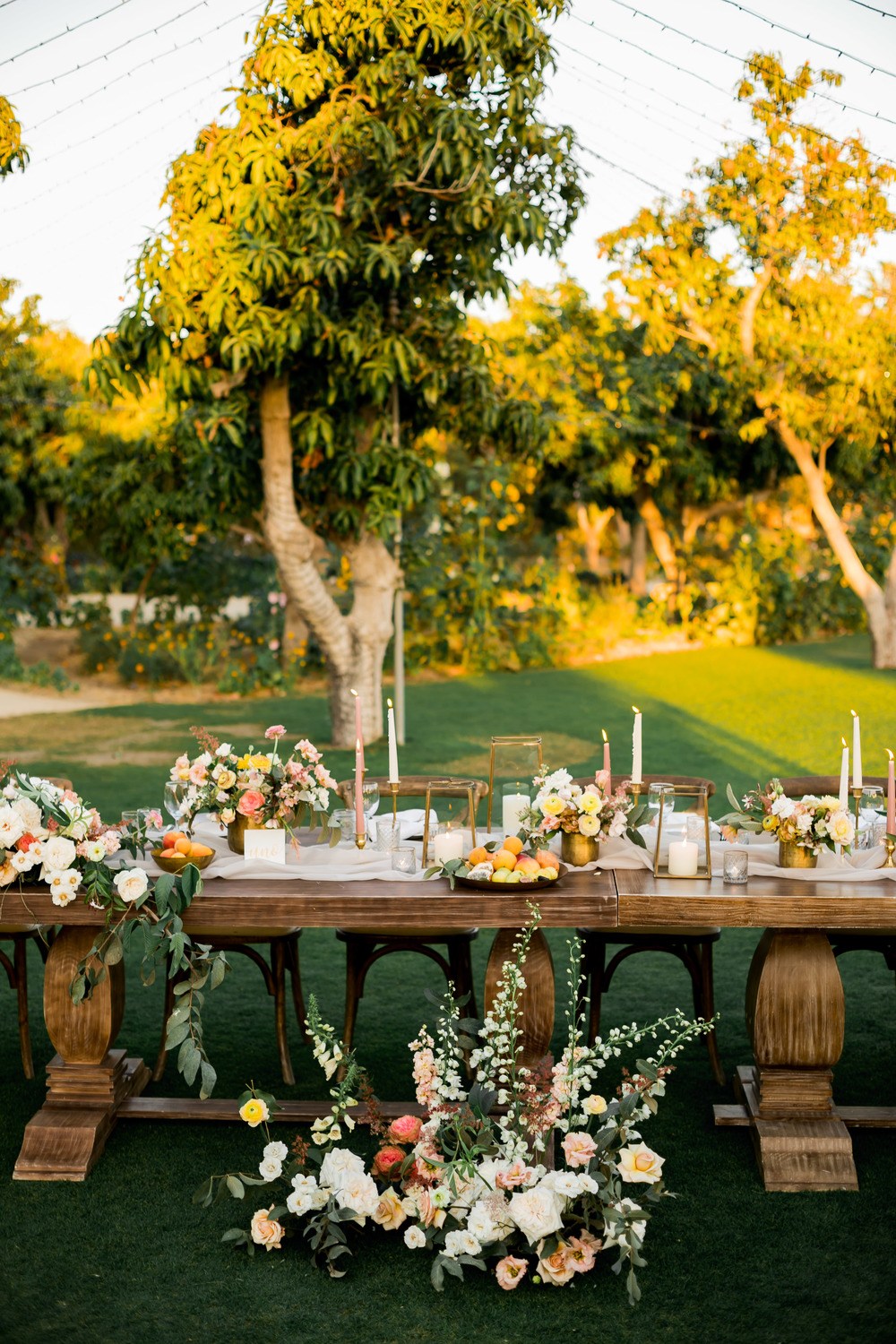 al fresco wedding tablescape with low wild centerpiece, thin wax candles and fruit bowls