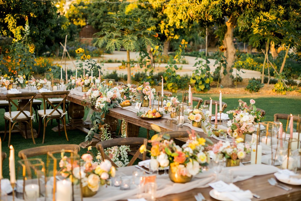 al fresco wedding tablescape with low wild centerpiece, thin wax candles and fruit bowls
