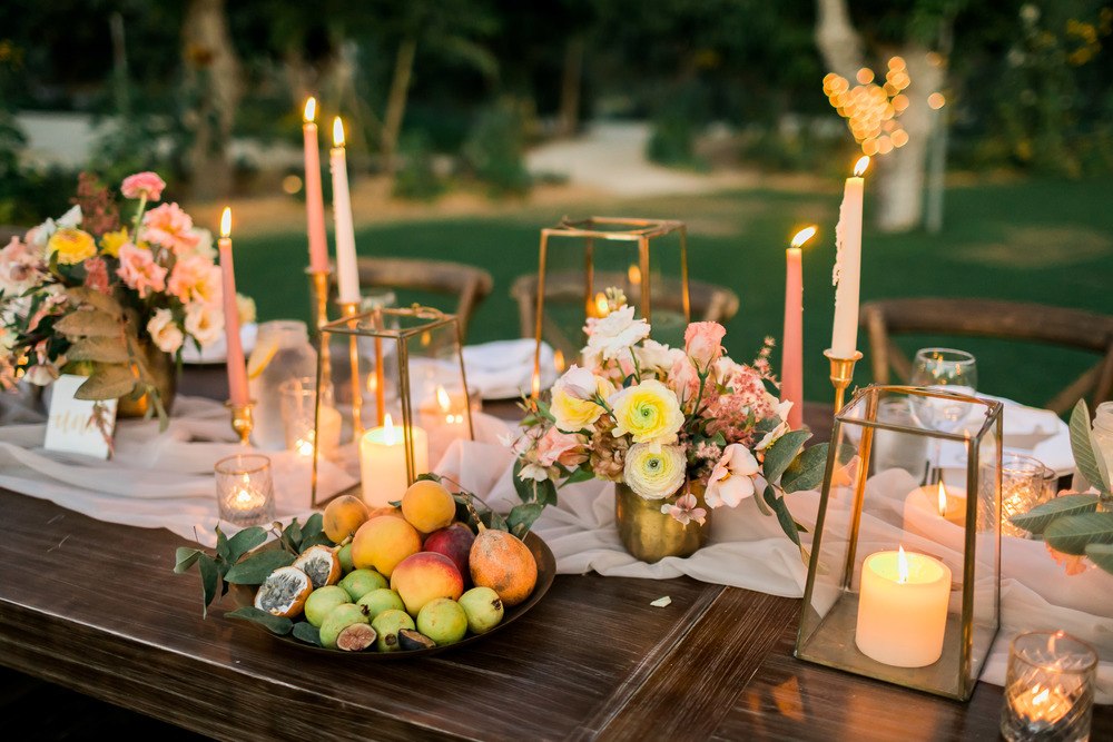al fresco wedding tablescape with low wild centerpiece, thin wax candles and fruit bowls
