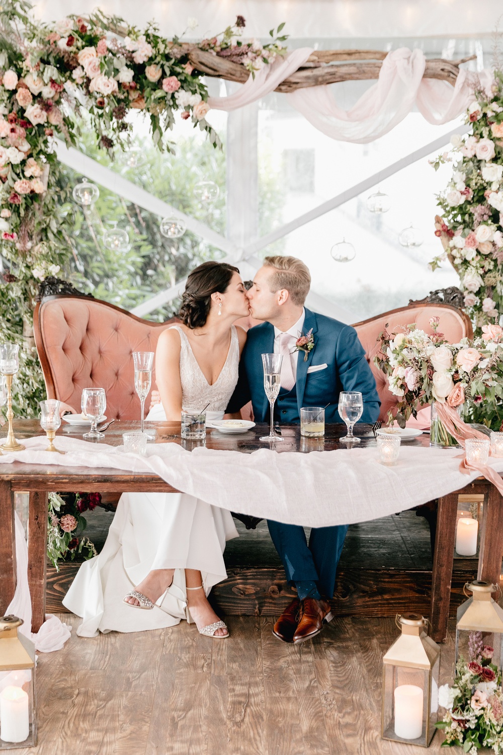 floral arch backdrop with a pink velvet sofa wedding sweetheart table