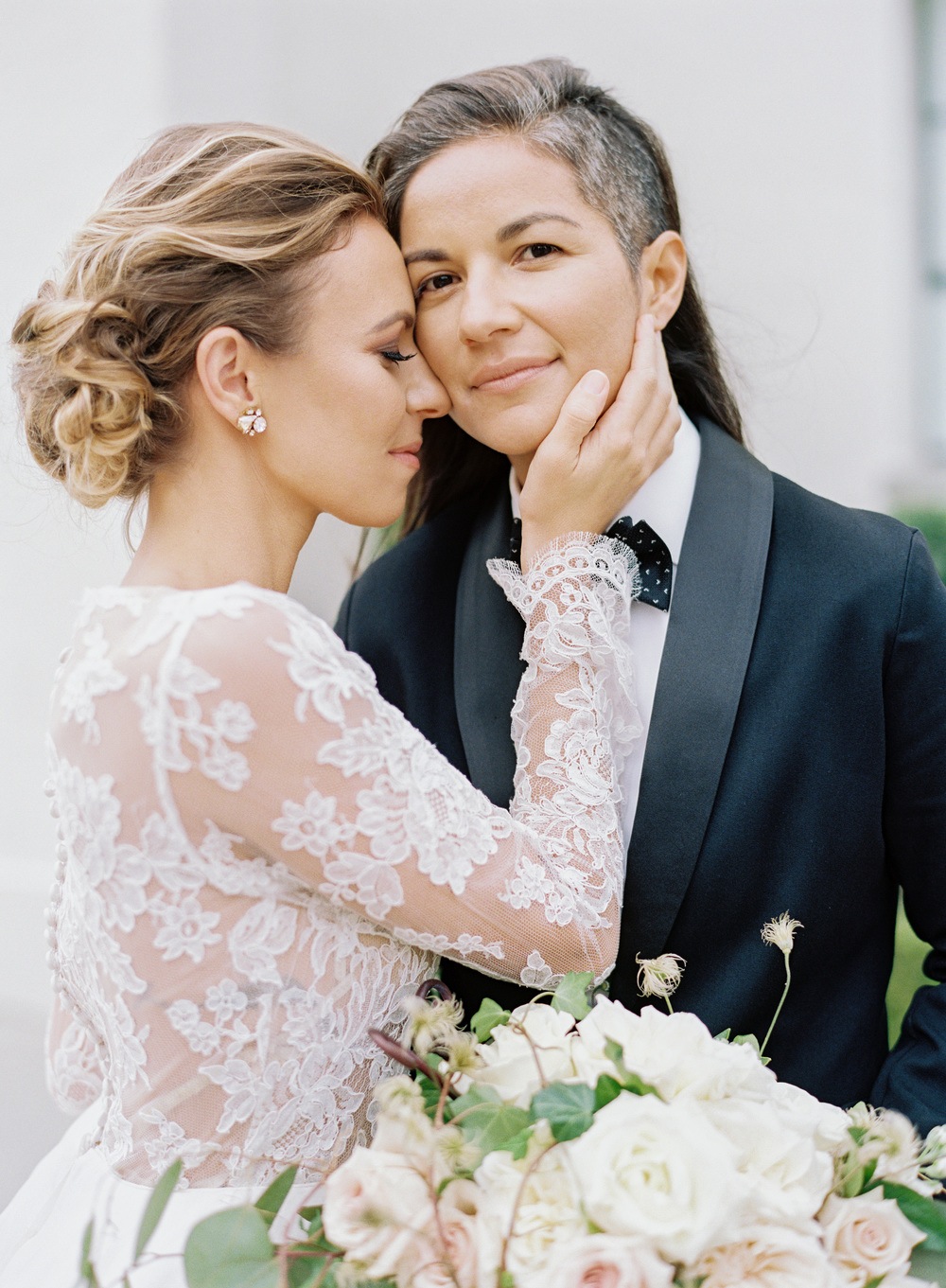 ruffled ballgown wedding dress with a black suit same sex wedding