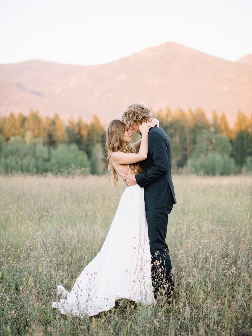 spaghetti strap wedding dress with flowy skirt and navy groom suit