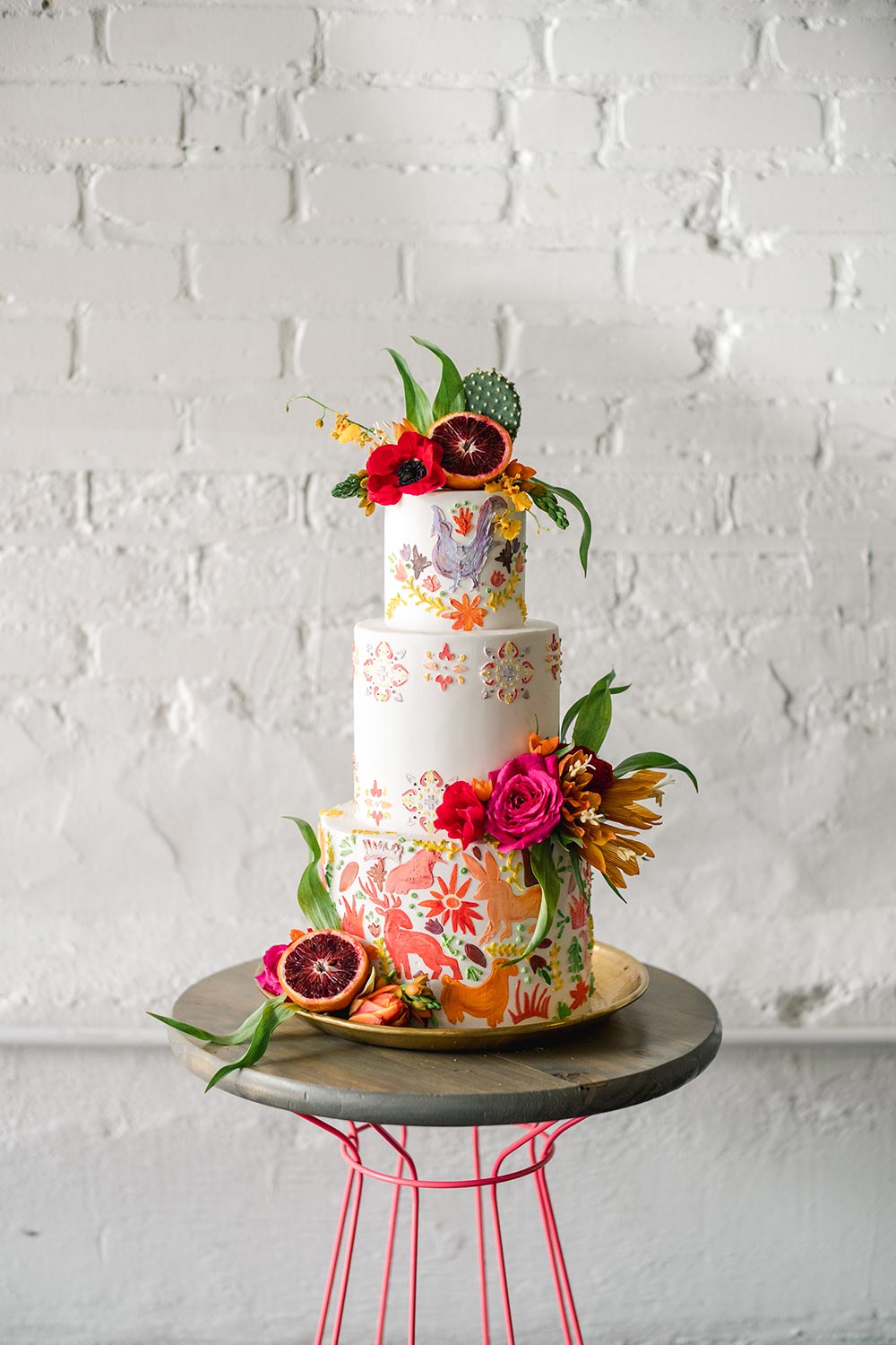 intricate Cinco de Mayo cake with colorful animal motifs, tropical flowers and pomegranate accents