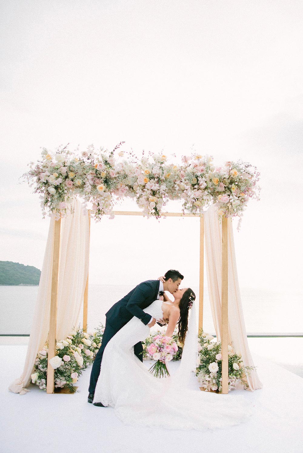 pink flower cabana wedding backdrop in Phuket destination wedding with bride and groom sharing a kiss