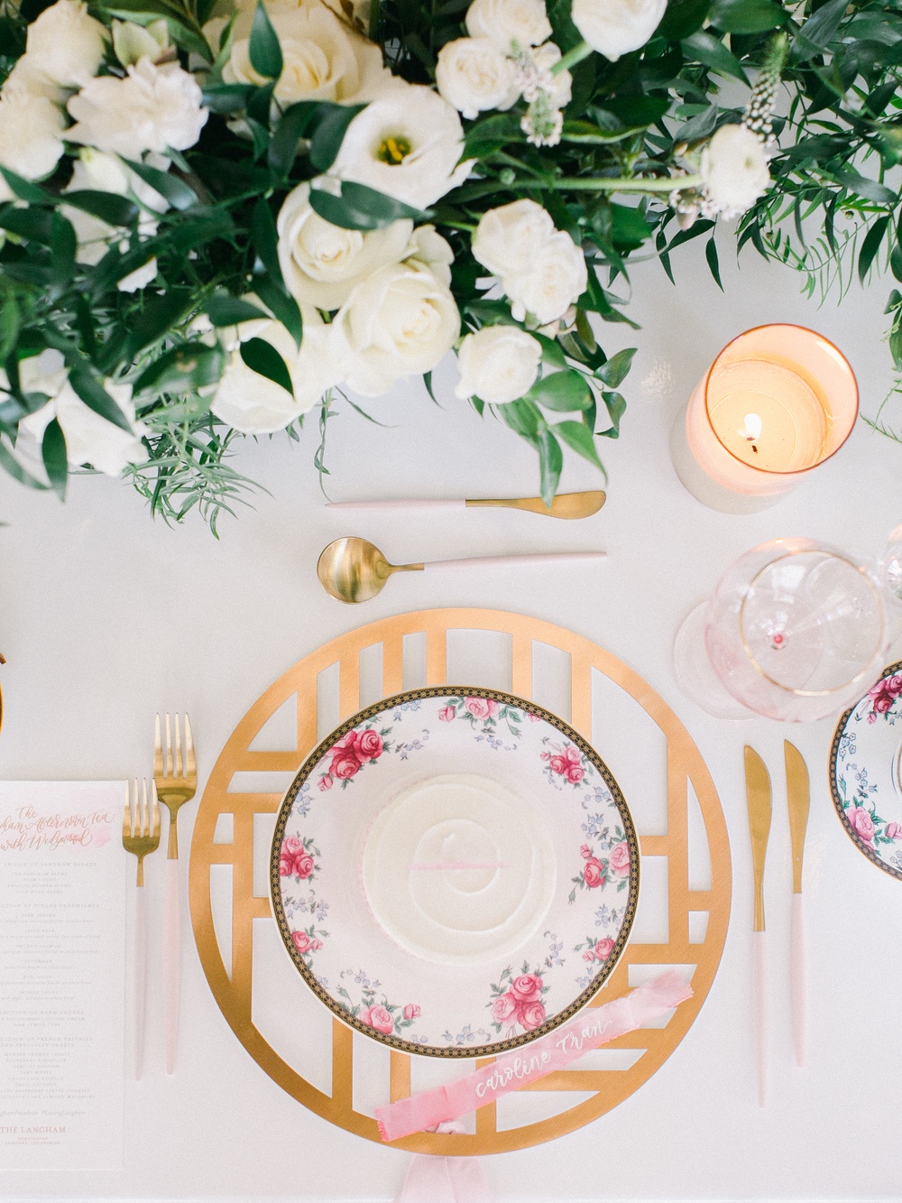 mini pink cake with rose colored wine glasses and a metallic copper charger