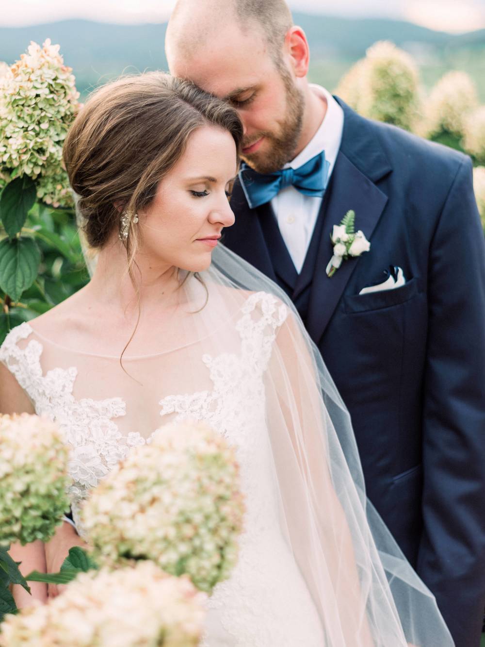 lace wedding dress with veil and navy groom suit