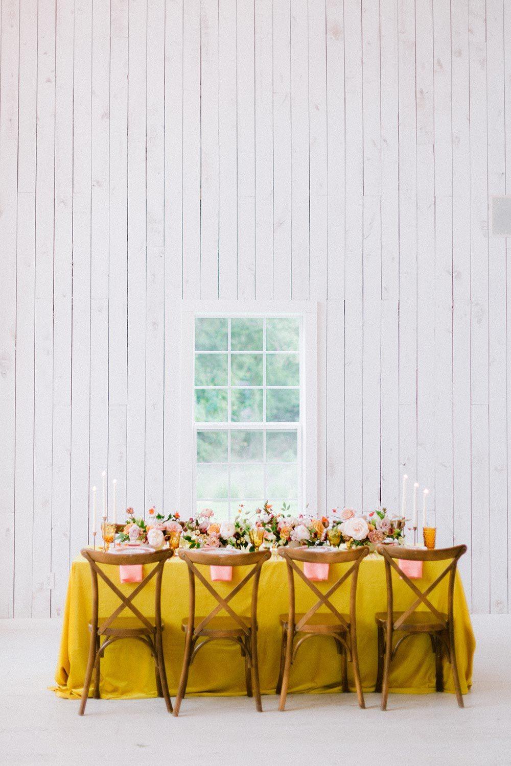  yellow wedding tablescape with cross back chairs and peach napkins