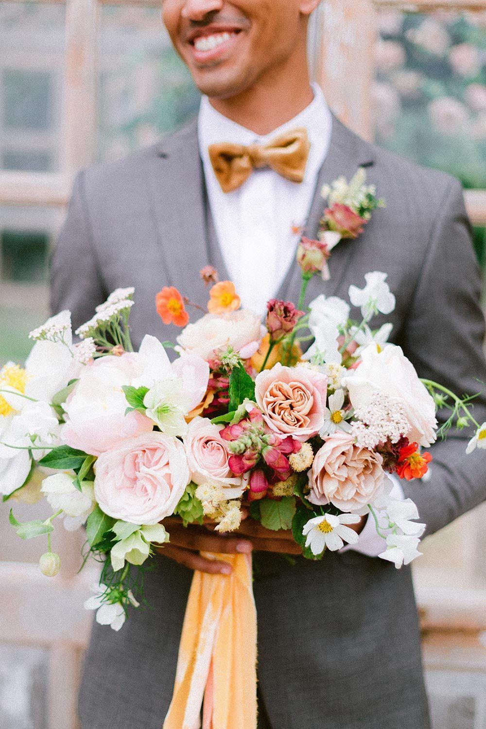 tailored gray groom suit with mustard velvet bow tie and rose boutonniere with vibrant summer bridal bouquet