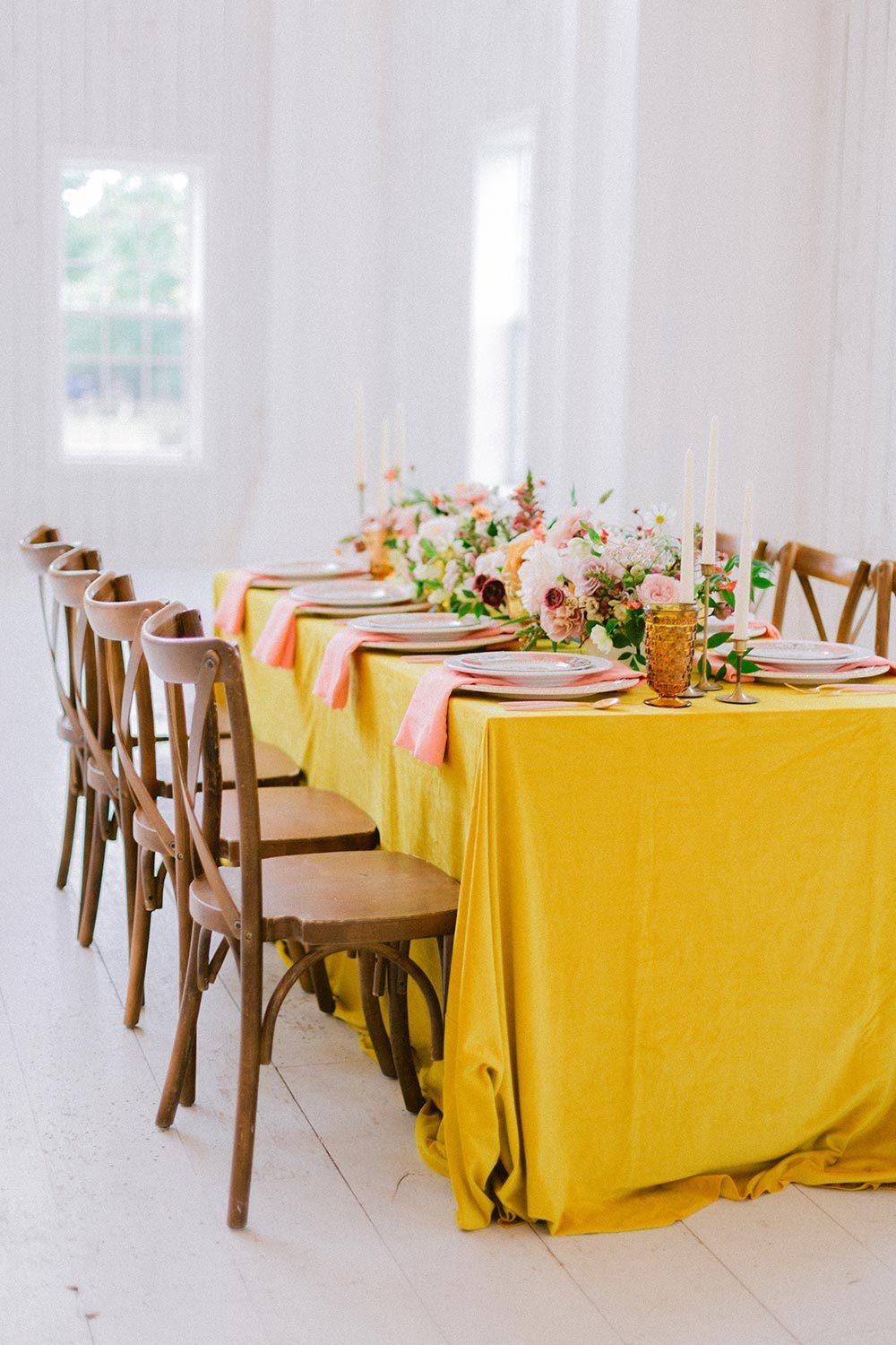 yellow wedding tablescape with cross back chairs and peach napkins