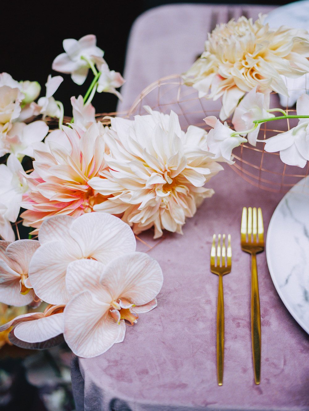 marble chargers with gold flatware on a velvet pink table linen